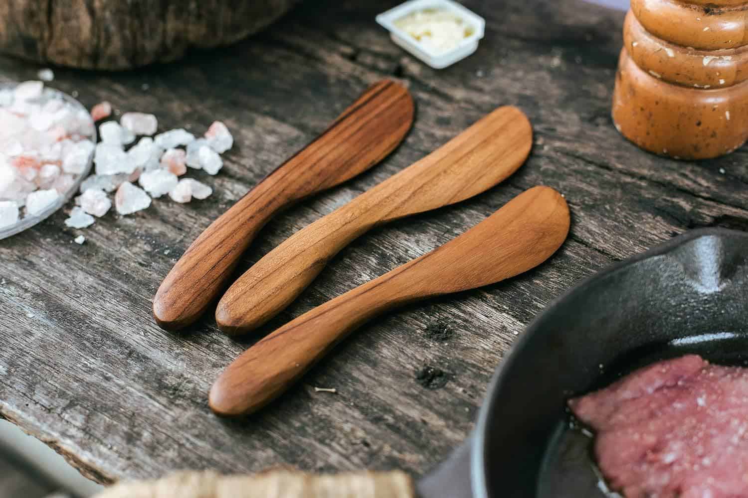 Natural wooden cooking spoons on rustic kitchen table, salt, and spices for gourmet cuisine.