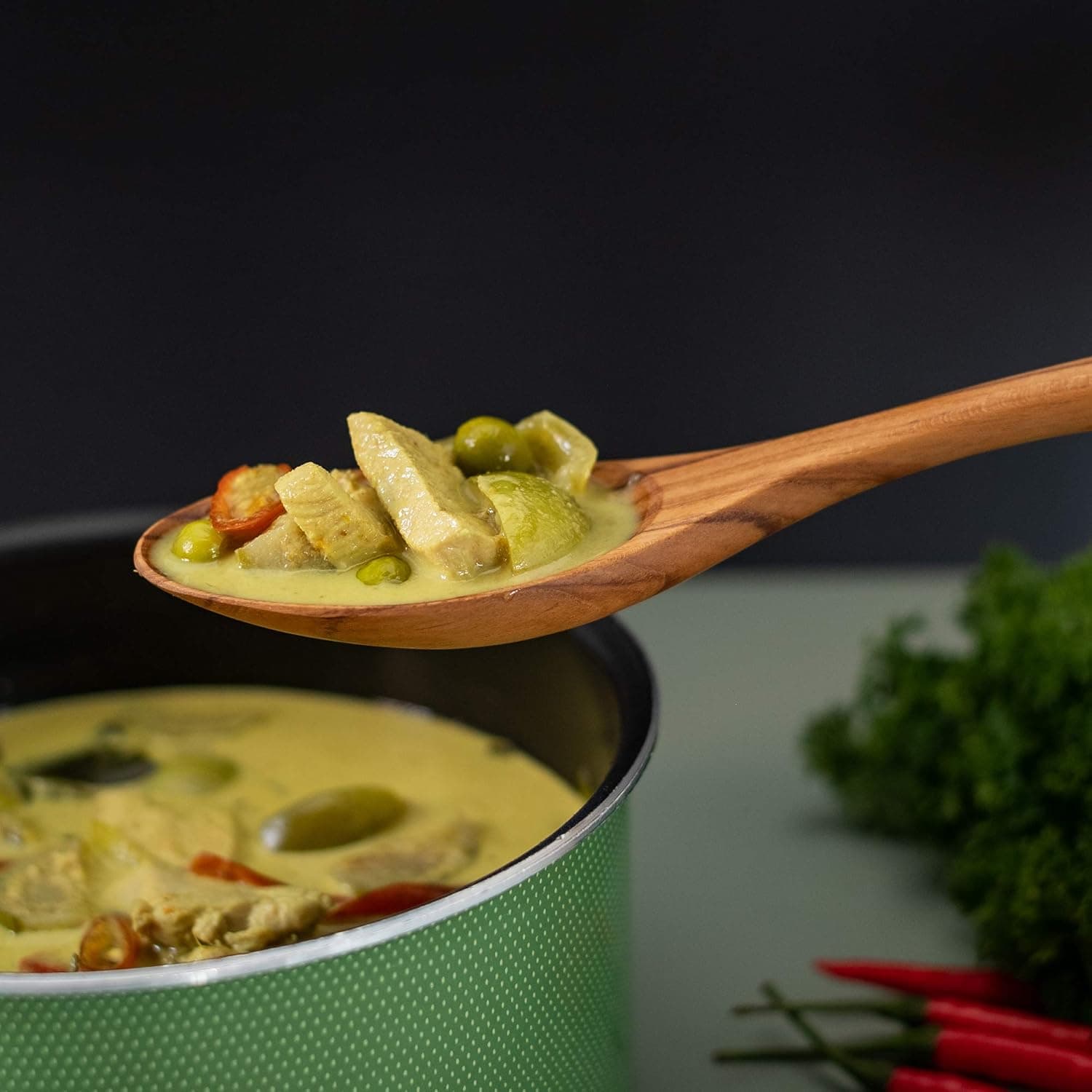 Delicious creamy chicken and vegetable stew served in a green pot with fresh herbs.
