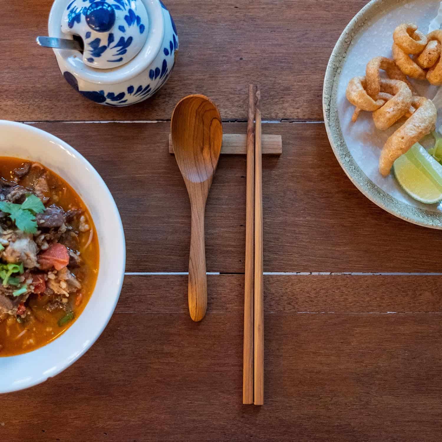 Traditional Asian dish with soup, crispy pork rinds, and fresh lime slices.