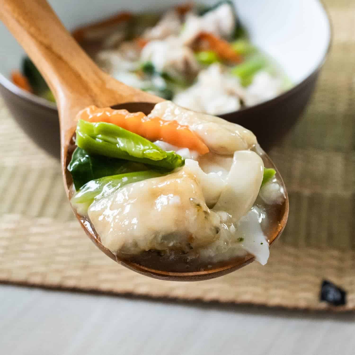 Delicious vegetable soup featuring fresh greens and tender chicken pieces in a wooden spoon.