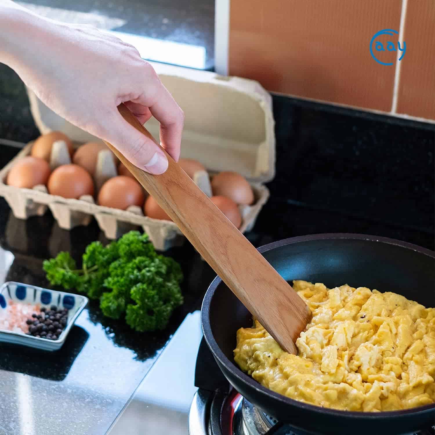 Eggs cooking in a black skillet with fresh ingredients on a modern kitchen countertop.