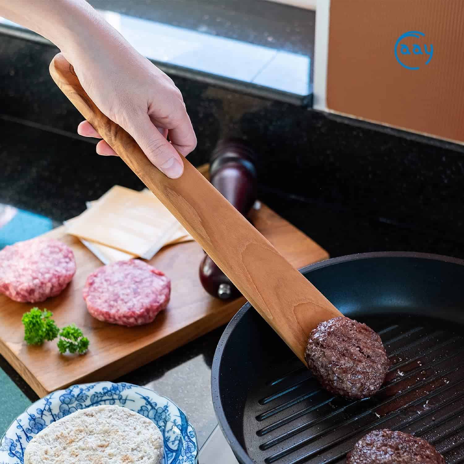 High-quality burger patties being cooked on a grill pan for home-cooked burger meal. Fresh ingredients and culinary tools visible.