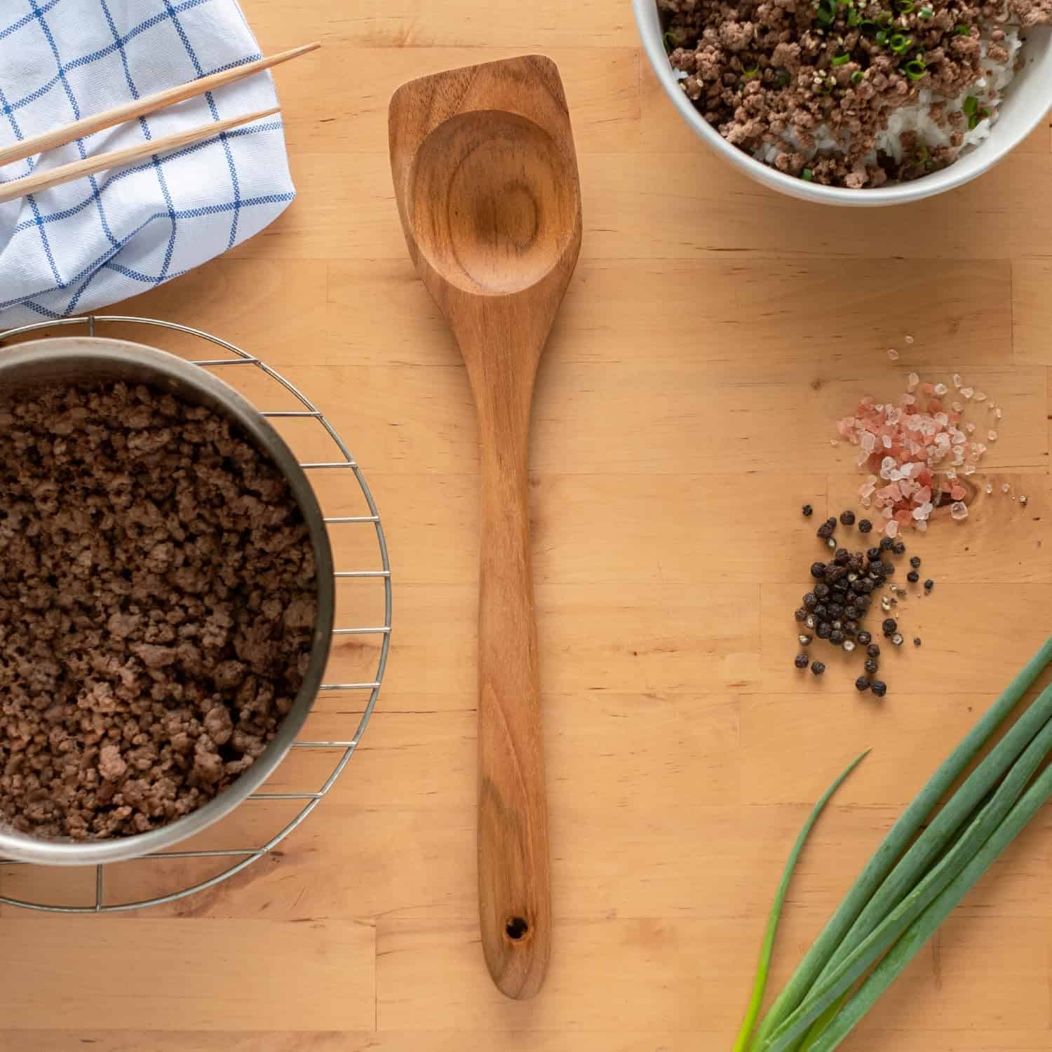 Rich, cooked ground beef with fresh herbs on a wooden kitchen surface. Perfect for home-cooked meals and recipes.