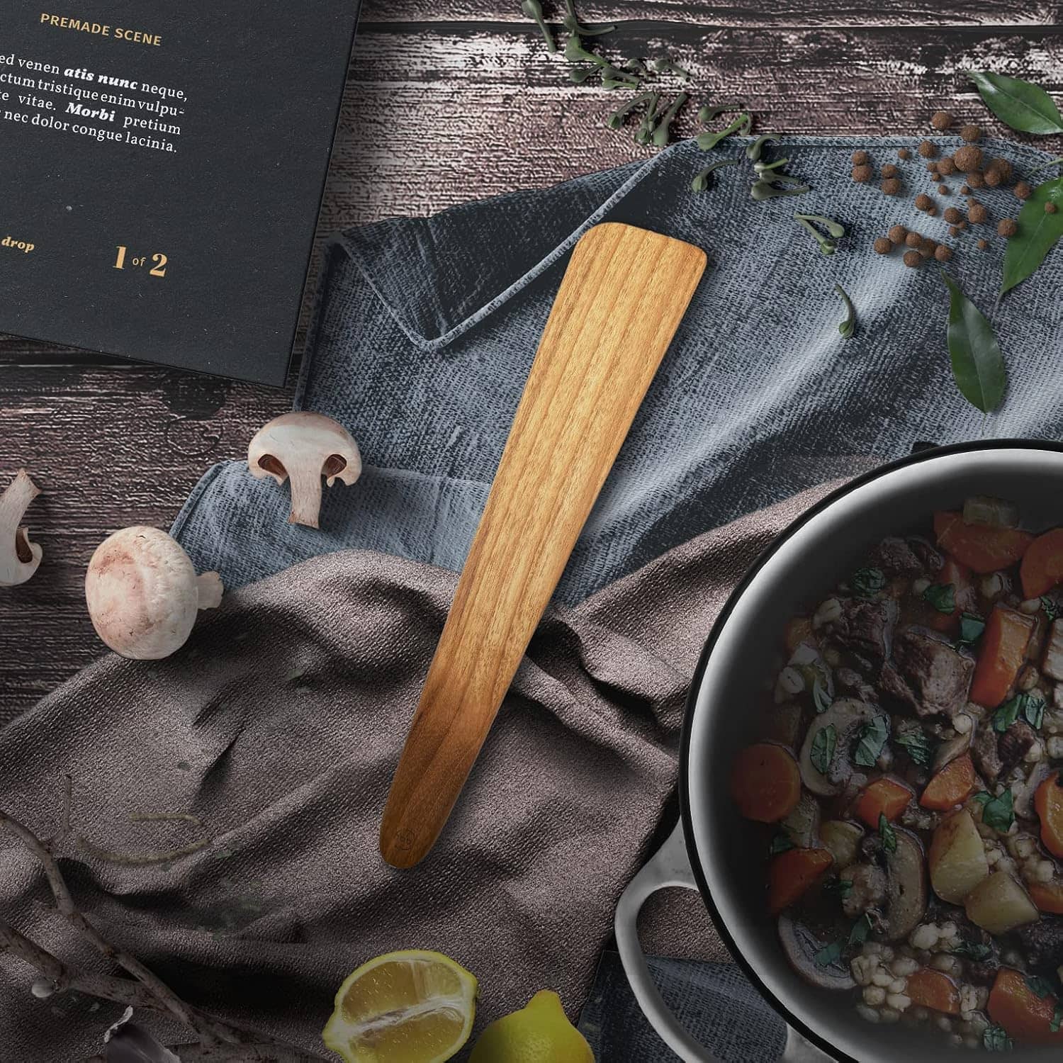Vibrant vegetable stew in a black pot with fresh herbs, set on textured cloth alongside mushrooms and lemon.